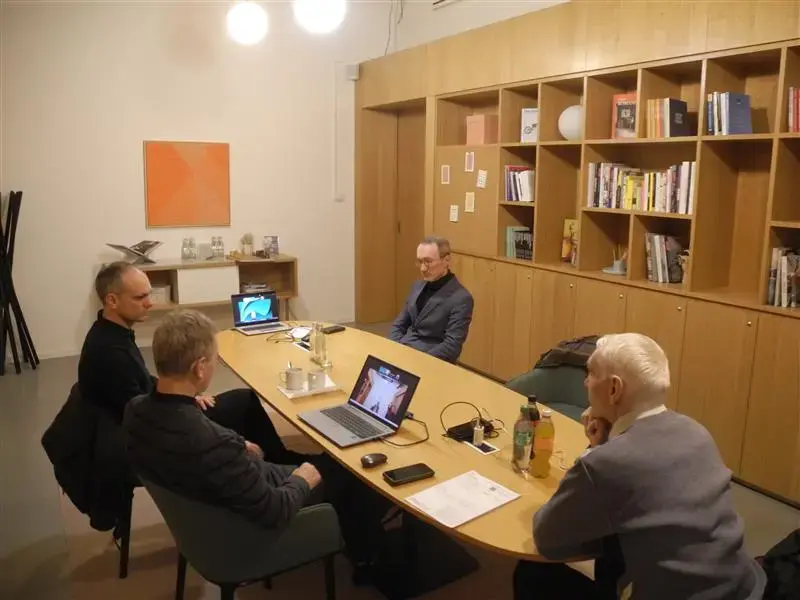 Project participants in a working session around a conference table, two laptops open and a presentation running.